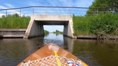 Canoeing on a canal passing a bridge towards Oudega in Friesland, The Netherlands