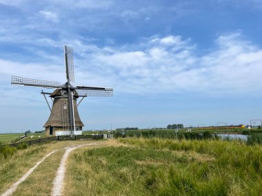 Hollanda, Friesland 'daki Vegelinsoord' da yel değirmeni ve tren.