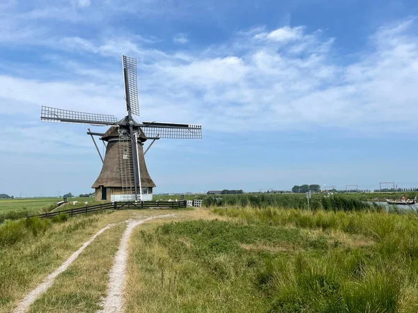 荷兰弗里斯兰的风车和一艘小船绕着峡湾航行 — 图库照片