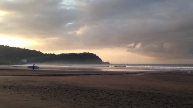 Sabahleyin Kosta Rika 'daki Jaco plajında sörfçü.