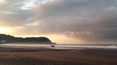 Sabahleyin Kosta Rika 'daki Jaco plajında sörfçü.