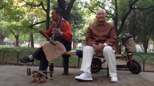 Eldre mann som spiller musikk i en park, Beijing, Peking, Kina – stockvideo