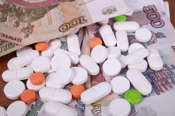 Pills of different colors on money background. — Stock Photo, Image