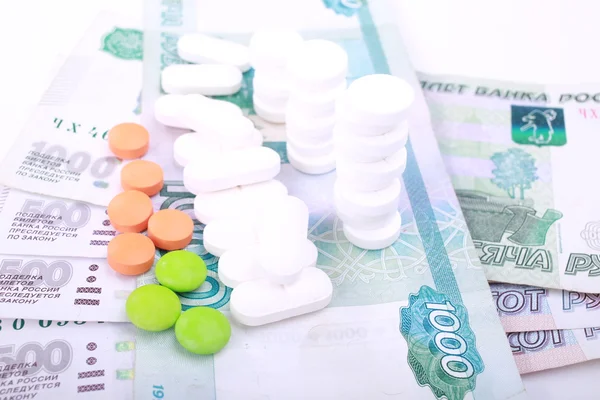 Pastillas de diferentes colores sobre fondo de dinero . — Foto de Stock