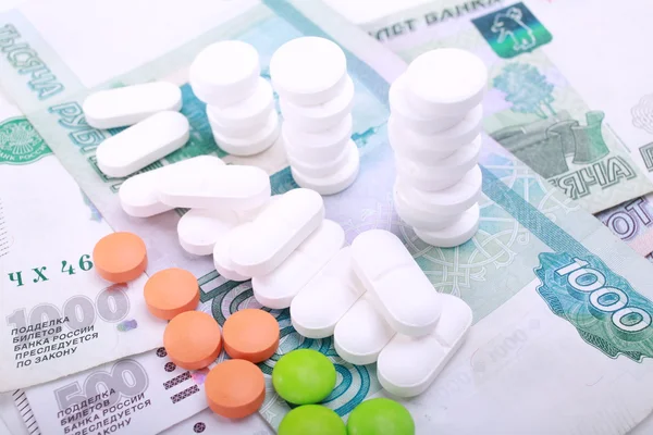 Pills of different colors on money background. — Stock Photo, Image