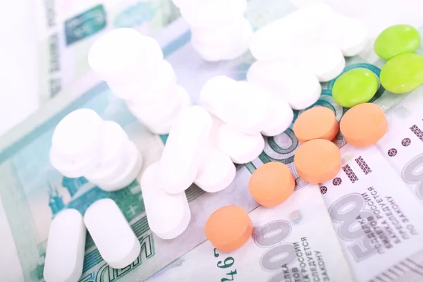 Pills of different colors on money background. — Stock Photo, Image