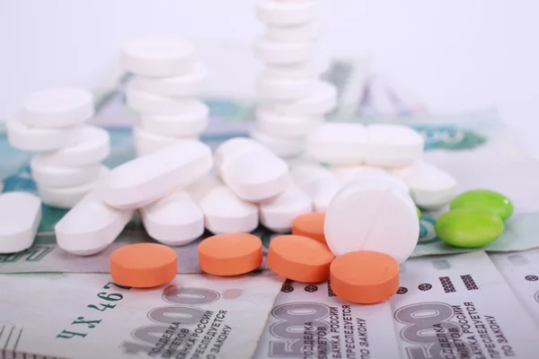 Pills of different colors on money background. — Stock Photo, Image