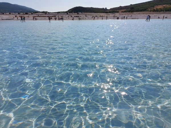 People walk in the shallow blue clear water of Lake — Stock Photo, Image