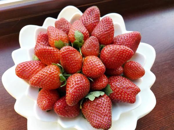 Dojrzałe czerwone duże truskawki na białym talerzu — Zdjęcie stockowe