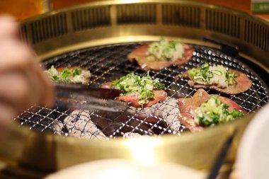 Japon / Kore mutfak restoranındaki kömürlü domuz diliyle yeşil soğan sosunu yakın..