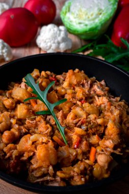 Sebzeli, patatesli, soğanlı, havuçlu, karnabahar, lahana, domates soslu, sarımsaklı ve otlu ev yapımı et yahnisi ahşap bir tabakta..