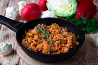 Geleneksel gulaş güveci sebze, patates, lahana, soğan, havuç, karnabahar, domates soslu biber, sarımsak ve otlar ahşap bir tabakta. Ahşap arka planda kırsal yemek