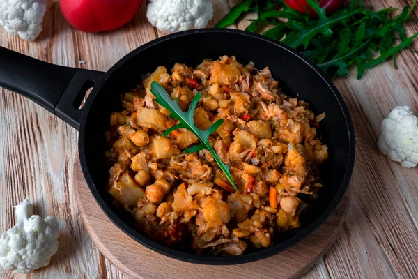 Sebzeli ev yapımı tavuk güveci, patates, soğan, havuç, karnabahar, domates soslu biber, sarımsak ve otlar ahşap masadaki kızartma kabında. Ahşap arka planda kırsal yemek
