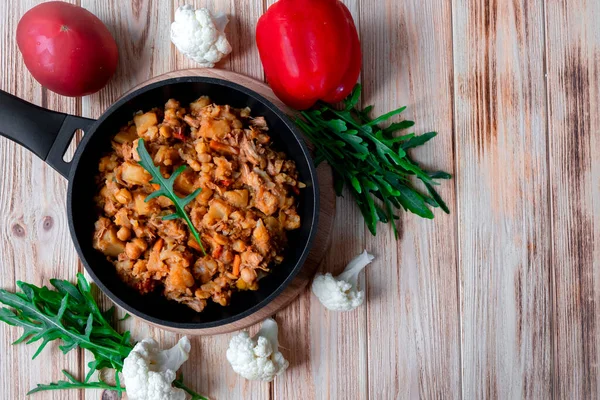 Sebze, patates, soğan, havuç, karnabahar, domates soslu biber, sarımsak ve otlu ev yapımı biftek güveci ahşap bir tavada. Kırsal düzlük. Uzayı kopyala Üst görünüm.