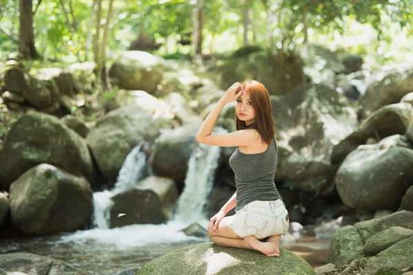 Ασία όμορφη σέξι κοπέλα κάθεται σε έναν βράχο στο νερό πέφτουν — Φωτογραφία Αρχείου