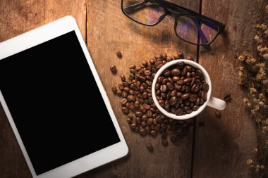 Kahve çekirdekleri ve ahşap masa gözlük ile tablet