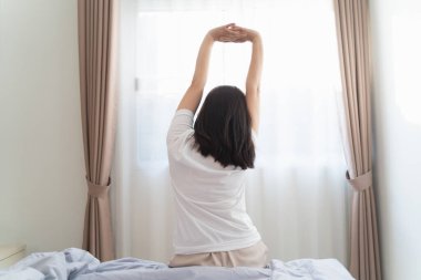 Asyalı kadın uyandıktan sonra yatak odasında geriniyor.