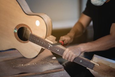 Zanaatkar tahta masada gitar yapıyor, Capenter çalışıyor.