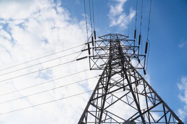 Yüksek voltaj postası. Mavi gökyüzünde yüksek voltaj kulesi ve arka planda bulutlar.