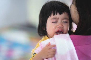 Asyalı şirin bebek, elinde anneye ağlıyor.