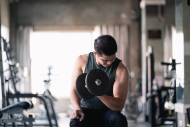 Spor salonunda dambıl egzersizi kullanarak yakın çekim yap.