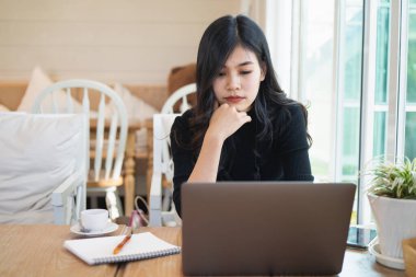 Genç kadınlar kafenin ahşap masasına dizüstü bilgisayarlarıyla ciddi ciddi düşünüyorlar.