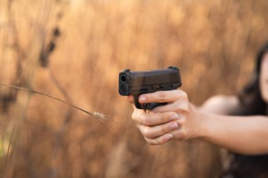 Güzel Asyalı kadınlar silahlarını kuru çimlere doğrultuyorlar.