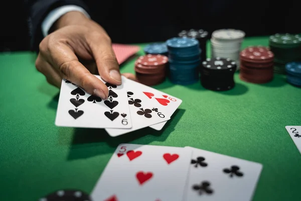 Satıcı ya da krupiye, poker konsepti olan bir masanın arka planında kumarhanede poker kartları karıştırıyor.
