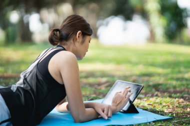 Genç bir kadın parkta bir video konferansında yoga egzersizi öğreniyor. Spor yoga konsepti.