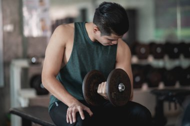 Spor salonunda dambıl egzersizi yapan adama yaklaş.