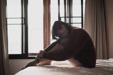 Yatak odasındaki yatakta oturan depresyonlu kadın.