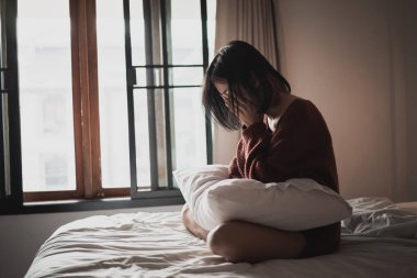 Yatak odasındaki yatakta oturan depresyonlu kadın.