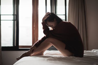 Yatak odasındaki yatakta oturan depresyonlu kadın.