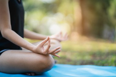 Parkta yoga egzersizi yapan genç bir kadın, spor yoga konsepti.