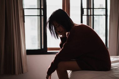 Yatak odasındaki yatakta oturan depresyonlu kadın.