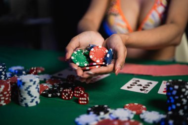 Kumarhanedeki poker masasında bikini giyen seksi kadınlar poker fişleri tutuyor.