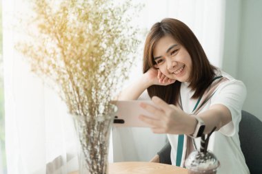 Güzel kız kafede cep telefonu fotografı çekerek gülümsüyor. Kahve ve kek yiyor.