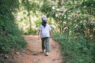Doğa Macerası 'nda Gün Işığı sırasında Ağaçlar ve Bitkilerle çevrili Çamurlu Yeşil Ormanda Yürüyen Çocuk