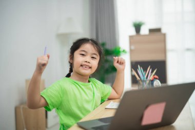 Genç Kız Renkli Kırtasiye ve Parlak Doğal Işıklı Konforlu Ev Ortamında Dizüstü bilgisayar Kullanırken Heyecan Gösteriyor