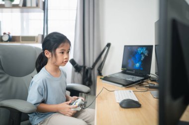 Evde heyecanla video oyunları oynayan genç bir kız, modern ve rahat bir ortamda rahat koltukta otururken ekrana odaklanmış.