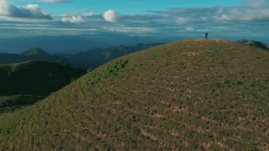 Mavi Gök Altında Bir Dağ Sırtında Duran Solo Yürüyüşçünün Manzarası Çevrelenmiş Yeşiller ve Arkaplanda Görkemli Bulutlar