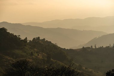 Serene Sunrise Over Rolling Mountains with Layers of Fog and Soft Light Casting Shadows through the Landscape in a Tranquil Environment