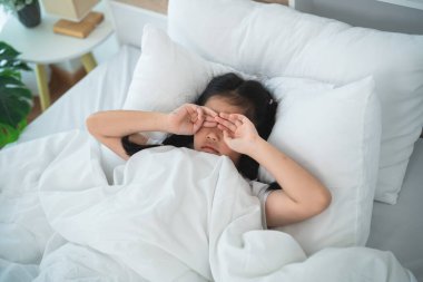 Yatakta Ovalayan Genç Kız Etrafı Sıcak Beyaz Battaniye ve Yastıklarla çevrili Sakin Bir Sabah, Uykulu Anları ve Evdeki Yaşamı Yakalıyor