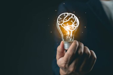 Ampulün içindeki insan beyninin yaratıcı kavramı motivasyon temalarının karanlık arka planına karşı fikirleri, yeniliği, düşünmeyi ve ilhamı temsil eder.