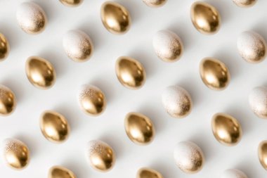 Beyaz arkaplandaki altın yumurtaların desenleri. Asgari paskalya kavramı.