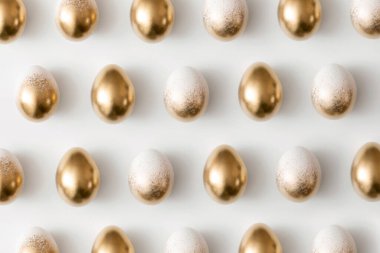 Beyaz arkaplandaki altın yumurtaların desenleri. Asgari paskalya kavramı.