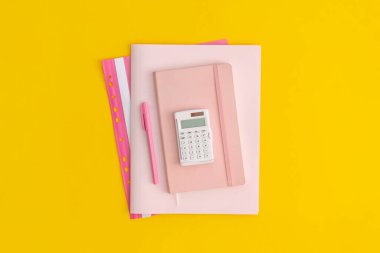 Sarı arka planda hesap makinesi, defter ve kalem. Üst Manzara. Düz yatıyordu. Okul konseptine dönelim..