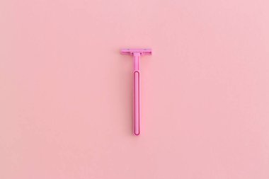 Pembe arka planda pembe plastik tıraş makinesi olan kadın. Kopyalama alanı olan üst görünüm. Düz konum.