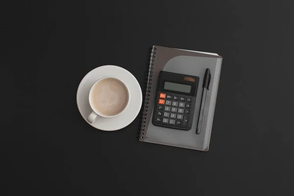 Taschenrechner Notizbuch Stift Und Eine Tasse Kaffee Auf Schwarzem Lederhintergrund — Stockfoto