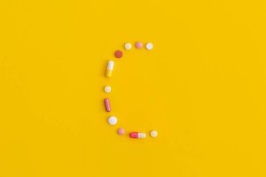 Sarı arka plandaki haplardan yapılan C vitamini. Kopyalama alanı olan üst görünüm. Düz yatıyordu.